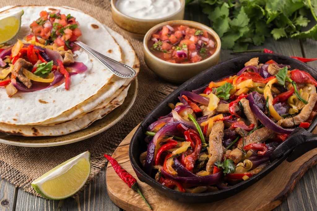 Pork fajitas with onions and colored pepper, served with tortillas, salsa and sour cream.